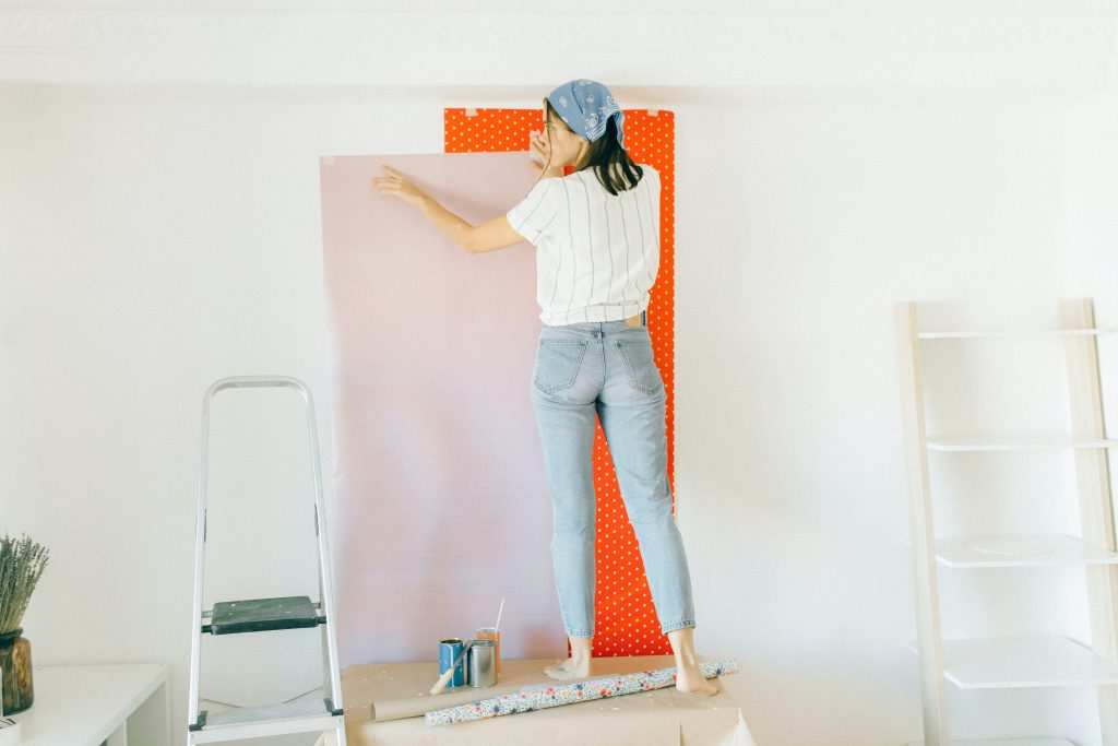 Frau hält rosa Tapete am Wand